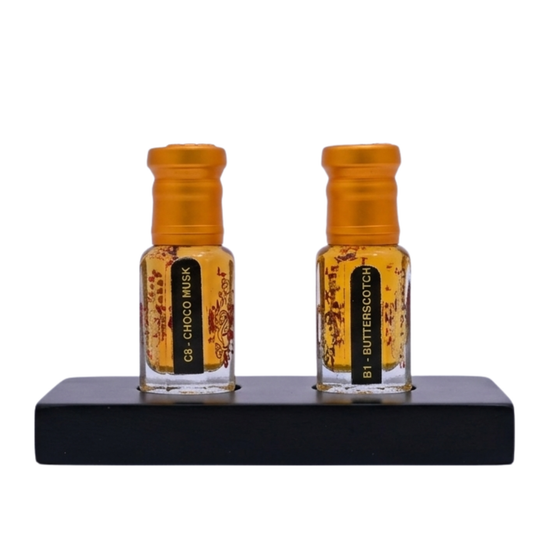 Two small bottles of perfume with orange caps on a black stand against a white background.