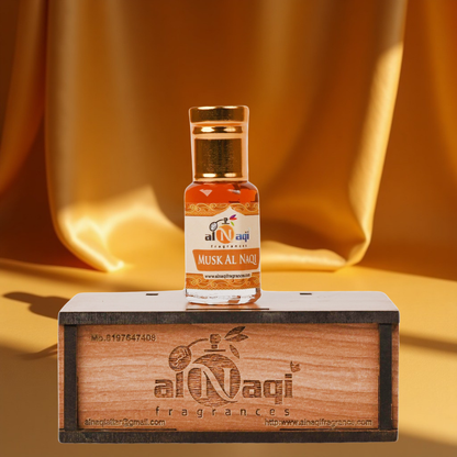 Small bottle of Musk Al Naqi perfume on a wooden stand with a gold fabric background
