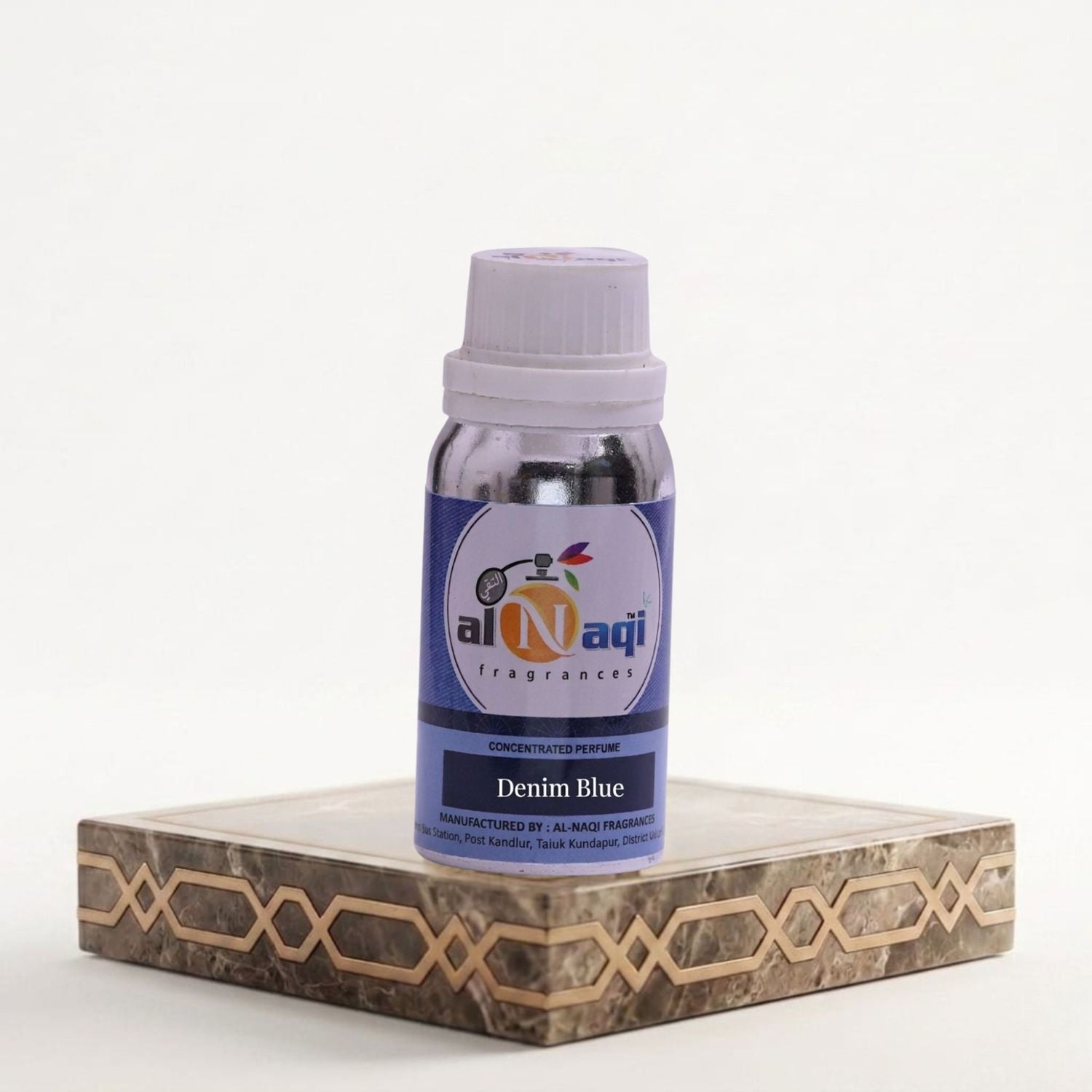 Bottle of Al-Naqi Denim Blue perfume on a decorative stand with a white background