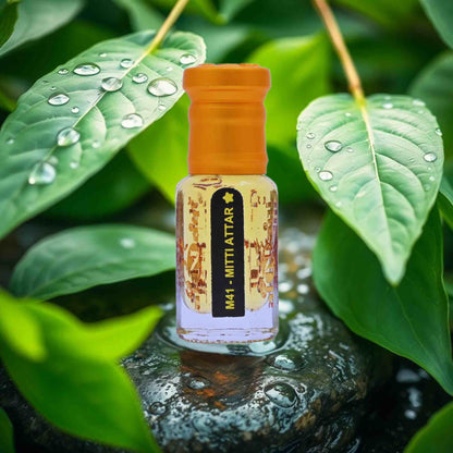 Small bottle with an orange cap on a stone surface surrounded by green leaves with water droplets.