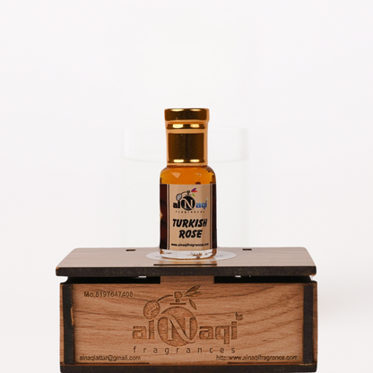 Small bottle of Turkish Rose perfume on a wooden stand with 'al-Naqi' branding.