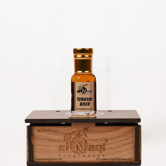 Small bottle of Turkish Rose perfume on a wooden stand with 'al-Naqi' branding.